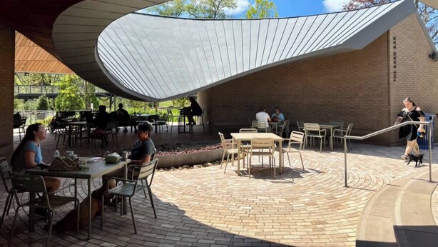 An outdoor dining area with tables and chairs under a curved roof structure. - Cary garden home close to SAS, RDU & RTP (Cary)