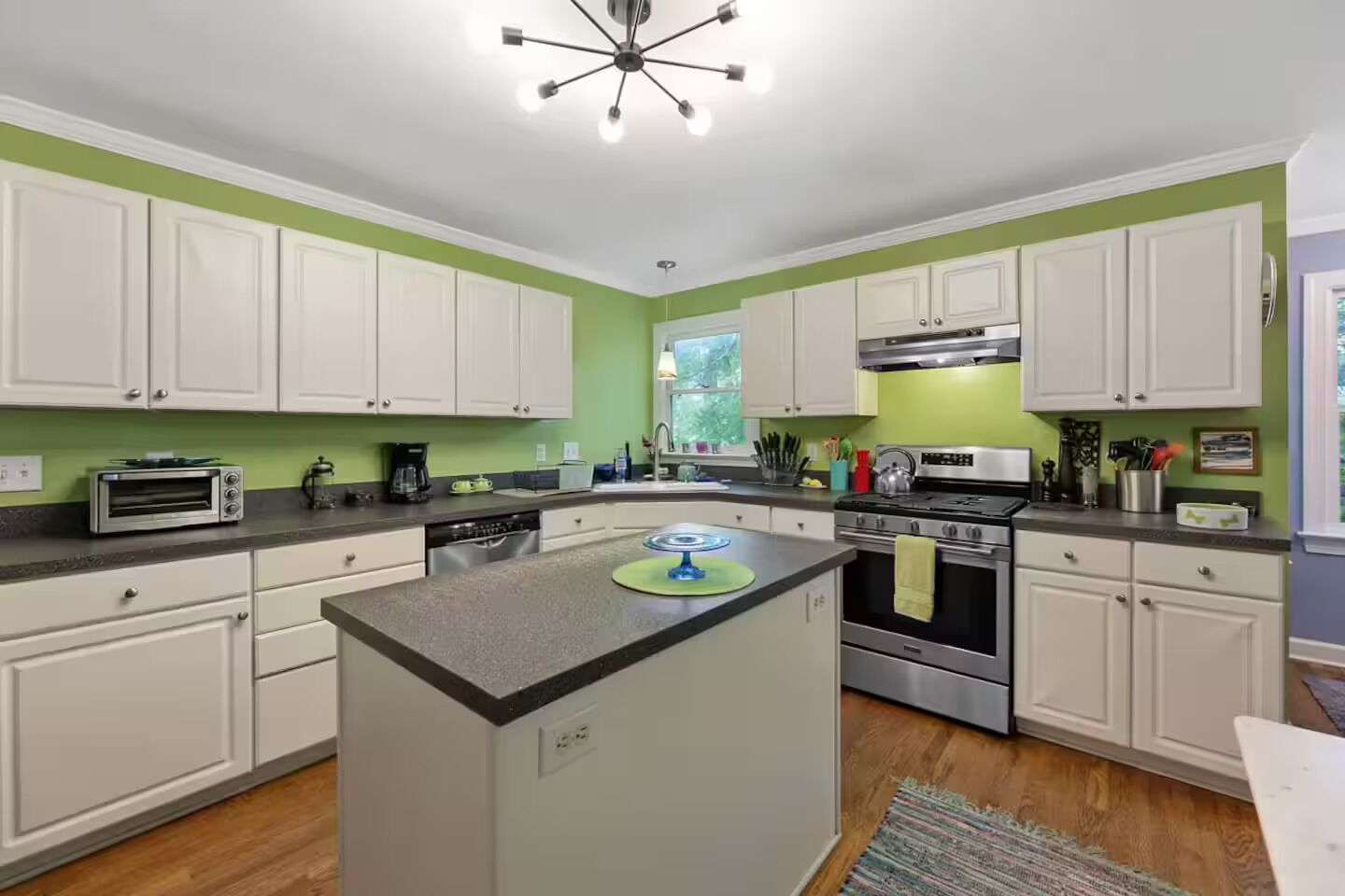 A kitchen with white cabinets, a central island, a stove, and a coffee maker.