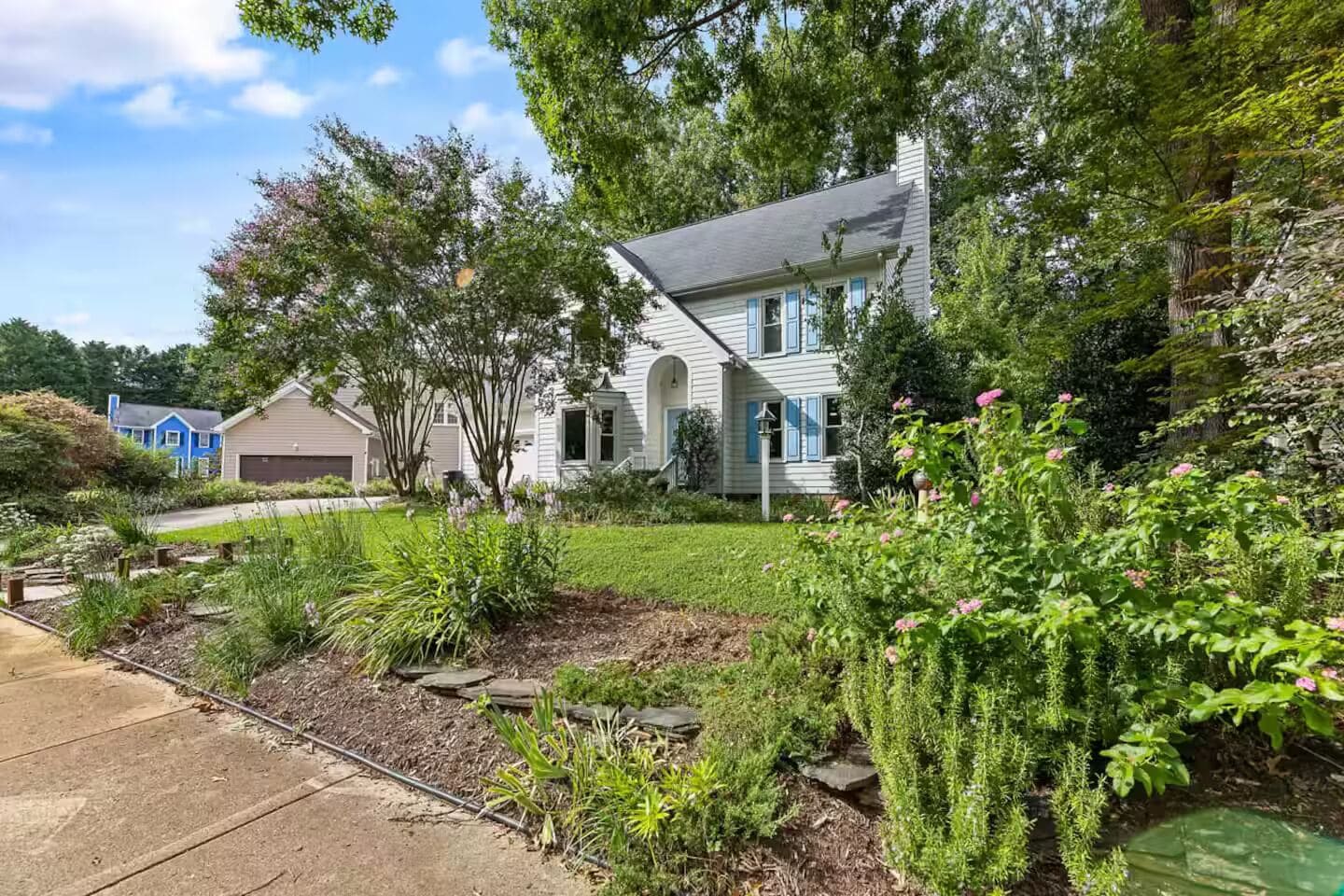 A residential property with a well-maintained garden, a driveway, and a garage.