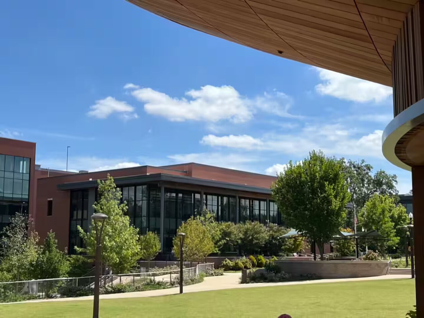 A modern building with large windows and a flat roof, surrounded by a well-maintained lawn and trees.