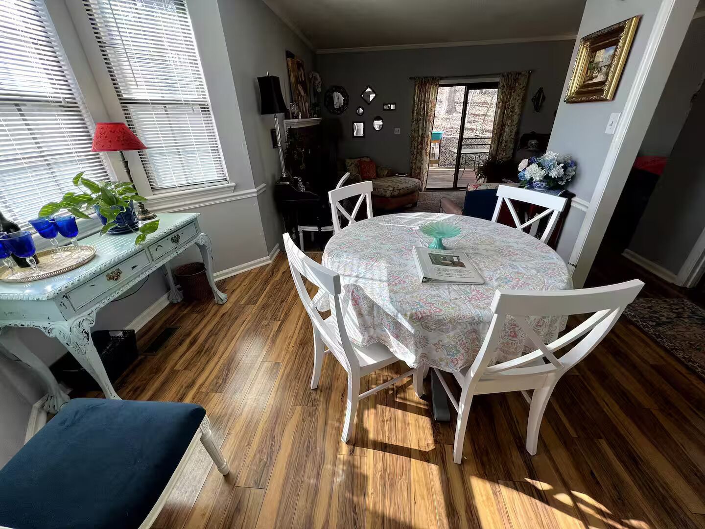 Un coin repas avec une table ronde, des chaises blanches, un banc bleu et une lampe de table décorative.