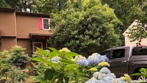 Un quartier résidentiel avec une maison, un camion et un jardin agrémenté d’hortensias.