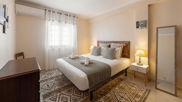Een hotelkamer met een bed, nachtkastje, lamp en spiegel.