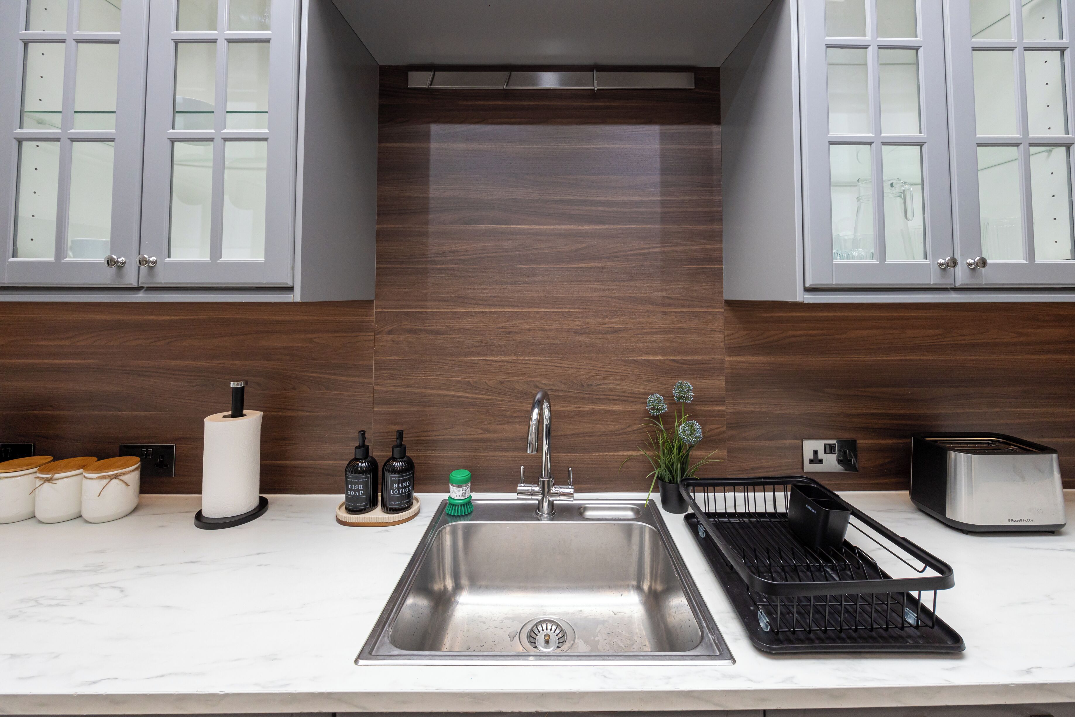 A modern kitchen with a stainless steel sink, a toaster, and a dish rack.