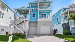 A multi-story residential building with a garage, a staircase, and a well-maintained lawn. - Ocean Pearl Vacation Rental (Fort Myers Beach)