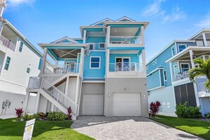 A multi-story residential building with a garage, a staircase, and a well-maintained lawn. - Ocean Pearl Vacation Rental (Fort Myers Beach)