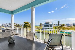 A balcony with a view of a pool, a lifeguard tower, and surrounding buildings.