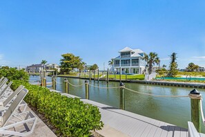 A waterfront property with a dock, lounge chairs, and a building with a balcony overlooking the water.
