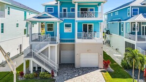 A multi-story residential building with a garage, a balcony, and a staircase leading to the entrance. - Ocean Pearl Vacation Rental (Fort Myers Beach)