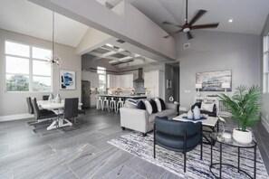 A spacious living area with a dining table, sofas, and a kitchen in the background.