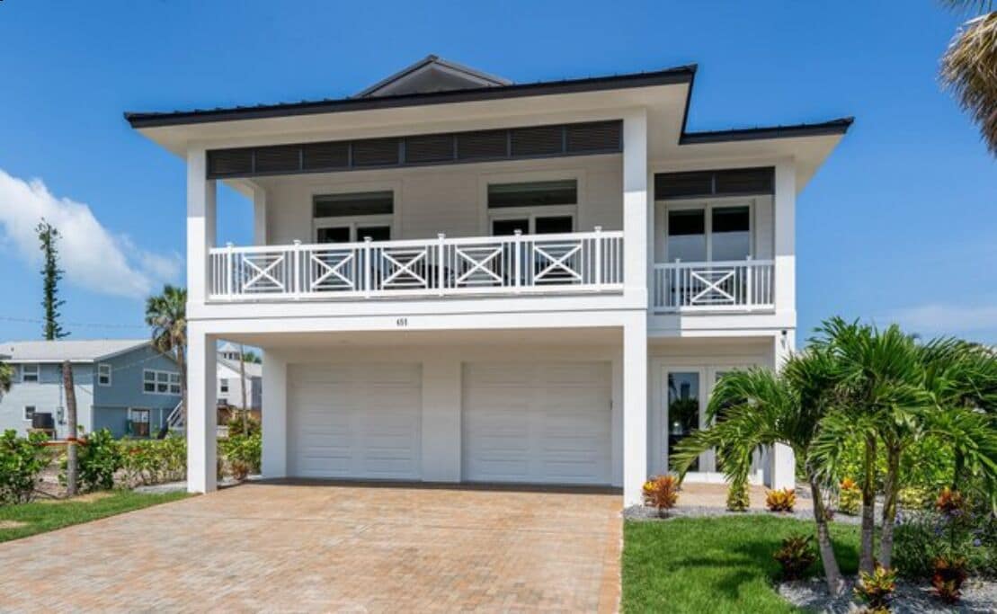 Une maison à deux étages avec un balcon, un garage et une pelouse bien entretenue.