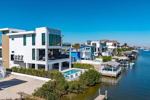 A waterfront property with modern architecture, a swimming pool, and docked boats.