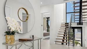 A modern interior with a large mirror, a staircase, and a view of the outdoors.