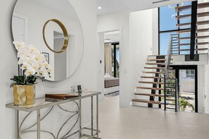 A modern interior with a staircase, a round mirror, and a welcome sign.