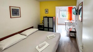 A hotel room with a bed, a desk, a chair, a TV, and a window with curtains. - 1 bedroom gorgeous apartment in Duce (Duce)