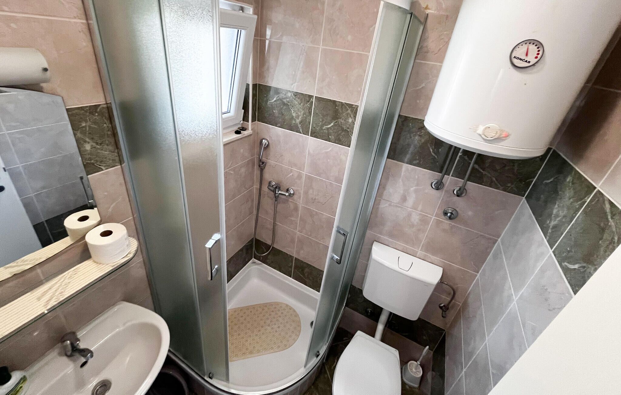 A small bathroom with a shower, toilet, and sink.