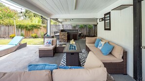 Une terrasse extérieure avec des meubles en osier, un foyer et une vue sur le jardin.