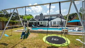 Un jardin avec une balançoire, un trampoline et une piscine.