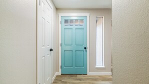 A hallway with a teal door, white walls, and a window with blinds. - Sapphire Lodge - 3 bed home in prime of Kennewick (Kennewick)