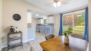 A modern kitchen with a blue backsplash, a dining area with a wooden table and chairs, and a view of a golf course through large windows. - Sapphire Lodge - 3 bed home in prime of Kennewick (Kennewick)