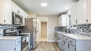 A modern kitchen with white cabinets, stainless steel appliances, and a tiled backsplash. - Sapphire Lodge - 3 bed home in prime of Kennewick (Kennewick)