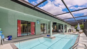 Une piscine couverte à l’eau claire, située à côté d’un bâtiment doté de grandes fenêtres et d’un rideau rouge.