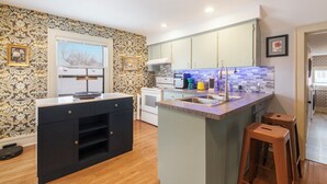 A modern kitchen with a central island, built-in appliances, and a patterned backsplash.
