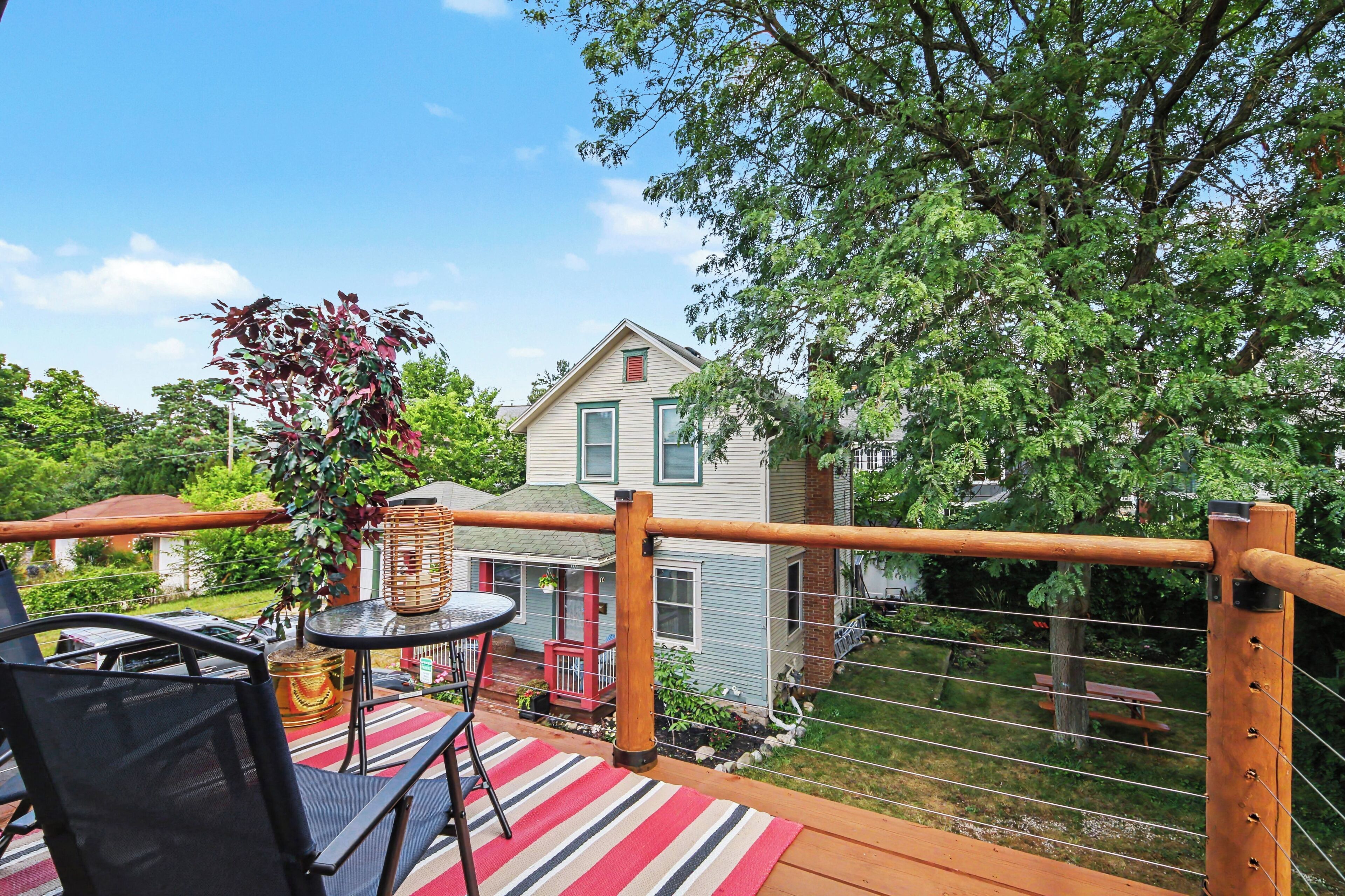 A deck with outdoor furniture, a railing, and a view of a house with a gabled roof.