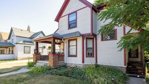 A two-story house with a front porch, a brick foundation, and a well-maintained lawn.
