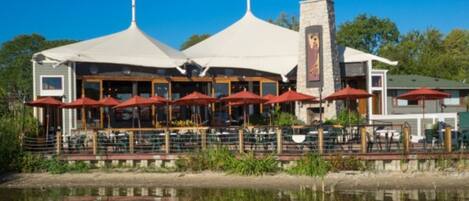 A waterfront restaurant with outdoor seating and a view of the water.