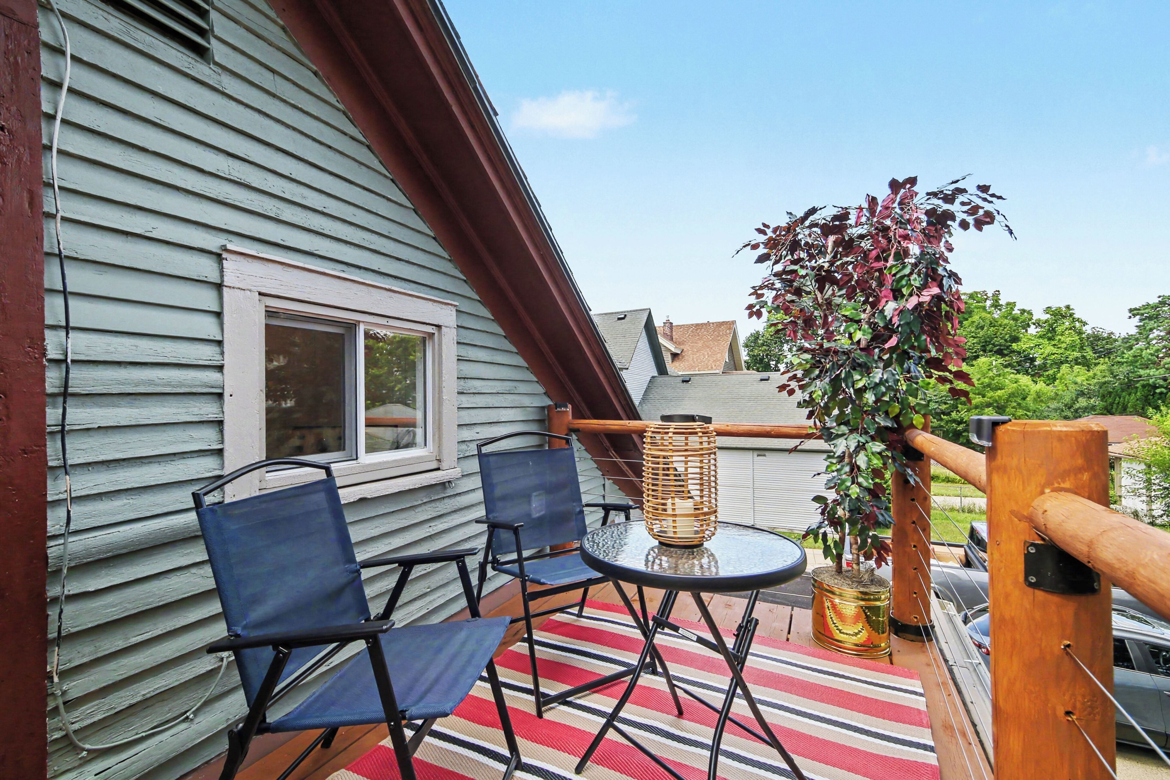 A balcony with two chairs, a table, and a potted plant.