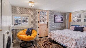 A bedroom with a bed, a chair, a television, and a door.
