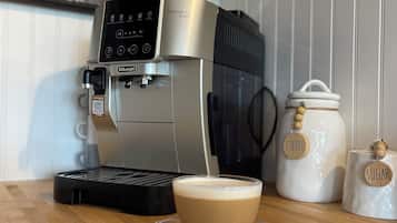 Una cafetera con una taza de café sobre una mesa de madera, junto a frascos etiquetados como 'Coffee' y 'Sugar'.