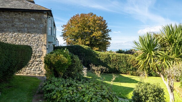 A stone building with a large tree in the background, surrounded by well-maintained hedges and a grassy lawn. - Spacious, cosy 5 bedroom home in the village of Seaview on the Isle of Wight views across the solent (Seaview)