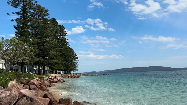 A beach with clear water, large rocks, and trees. - Solace by the Bay (Corlette)