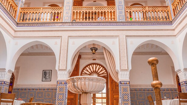 An ornate interior with arches, a fountain, and a large brass pot. - Abraj Bladi Resort (Marrakech)