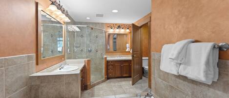 A modern bathroom with a large bathtub, a glass-enclosed shower, and wooden cabinetry.