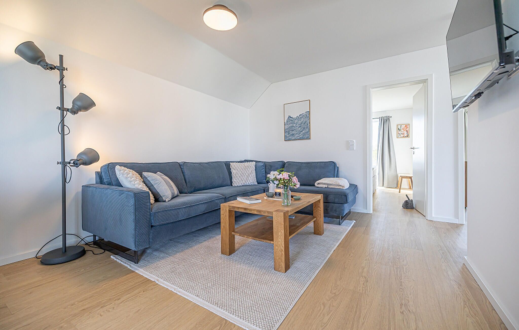 A modern living room with a blue sofa, a wooden coffee table, and a floor lamp.