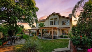 A two-story house with a patio, outdoor seating, and a well-maintained garden.