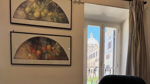 Un salon avec un canapé foncé, une table bleue et deux œuvres d’art encadrées représentant des fruits.