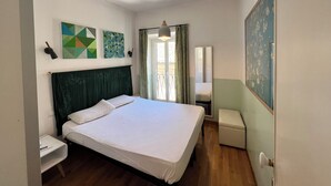 Une chambre à coucher avec un lit, des tables de chevet, un miroir et des œuvres d’art accrochées aux murs.