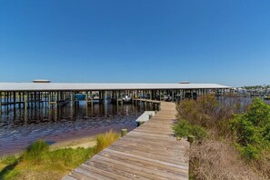 A wooden pier extending into calm water, with boats docked and a covered area at the end.