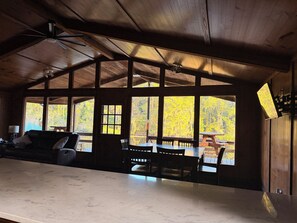 L'intérieur d'une cabane comprend un coin repas, un canapé et de grandes fenêtres donnant sur la forêt.
