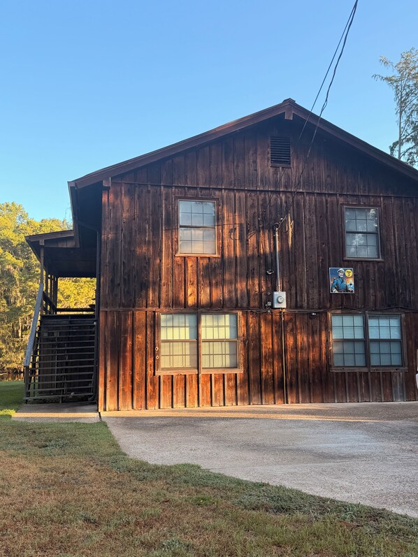Un bâtiment rustique en bois, doté d’un porche couvert et d’une entrée clôturée.