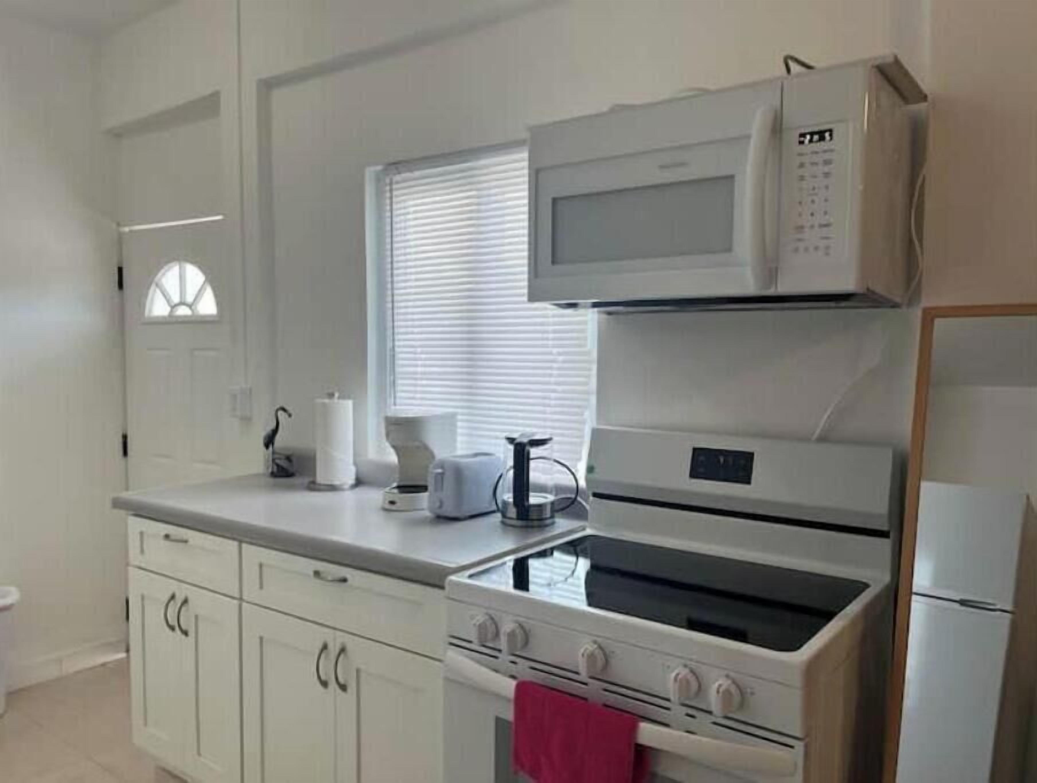 A kitchen with white cabinets, a microwave, a toaster, and a stove.