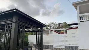 Un espacio de estar al aire libre cubierto con una estructura de metal para parrilla, una silla y una mesa.