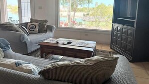 A living room with a sofa, a coffee table, and a television. - Waterfront 2-BR Home in Providenciales (Turtle Cove)