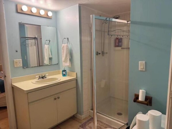 A bathroom with a sink, mirror, and glass shower enclosure.