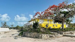 Un edificio giallo con un balcone, immerso nel verde sotto un cielo sereno.