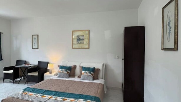Ein Schlafzimmer mit einem Bett, einem Schreibtisch mit Stuhl, einer Lampe und einem gerahmten Bild an der Wand.